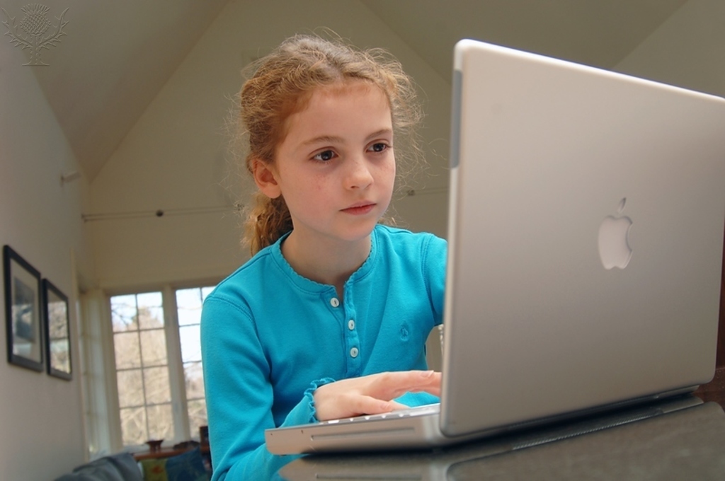 Girl using an Apple laptop computer at home.